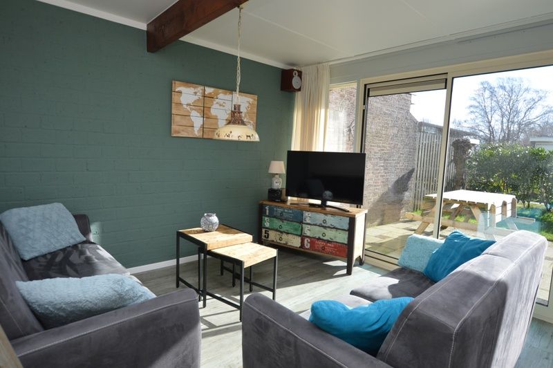 Lichtovergoten woonkamer met uitzicht op de tuin in Bungalow Verste Coogh 66, De Dennen, Texel.