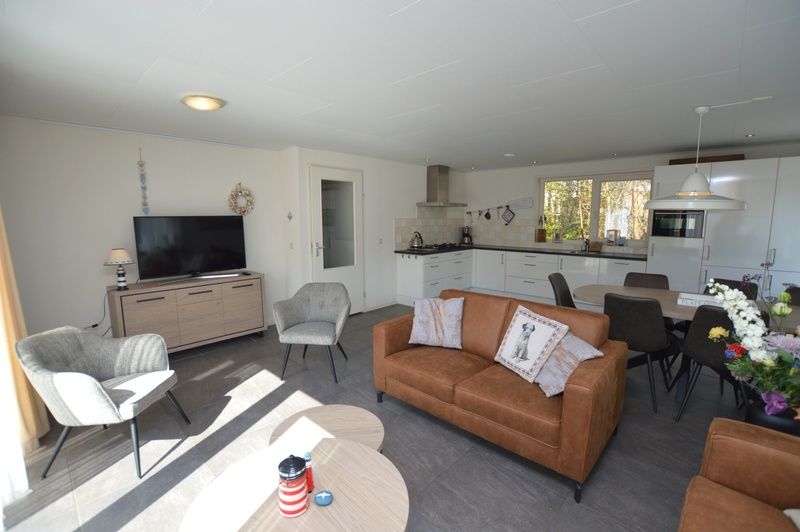 Gemuetlicher Wohnbereich im Holiday home de Parel 190, Texel mit Fernseher und Sitzecke.