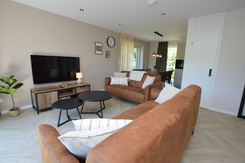 Modernes Wohnzimmer im Bungalow 't Hoogelandt 58, Texel, mit bequemen Sofas und stilvollen Moebeln.