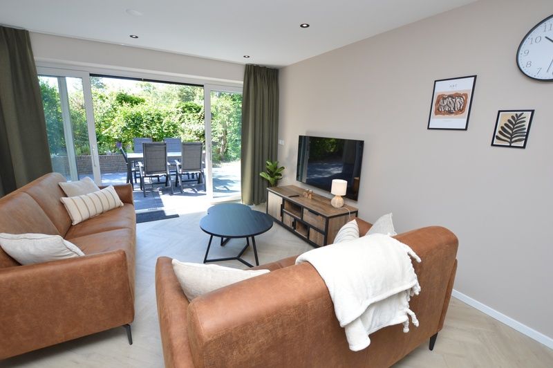 Geraeumiges Wohnzimmer des Bungalows 't Hoogelandt 58, Texel, mit Zugang zur sonnigen Terrasse.