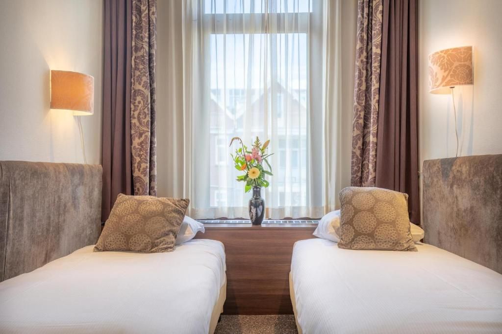 Knusse tweepersoonskamer in Hotel Milano, vakantieappartement in Rotterdam, met grote ramen en stijlvolle decoratie.