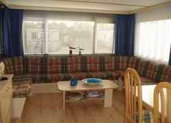 Gemtliches Interieur des Mobilheims Achaa in Formerum, Terschelling, mit bequemer Sitzecke und viel Licht.