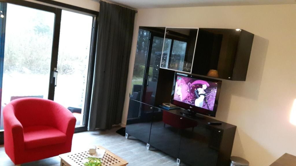 Gezellige zithoek in Appartement HELIOS - Amelander Kaap met ZWEMBAD, Hollum, Ameland, met comfortabele stoelen en tv.
