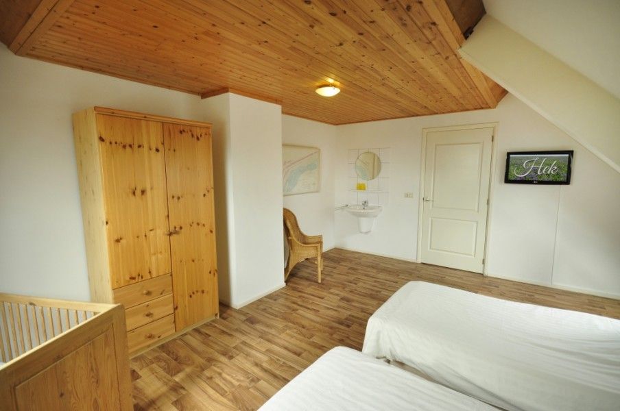 Ruime slaapkamer in Appartementenboerderij de Hek Oost, Hoorn, Terschelling met houten interieur.