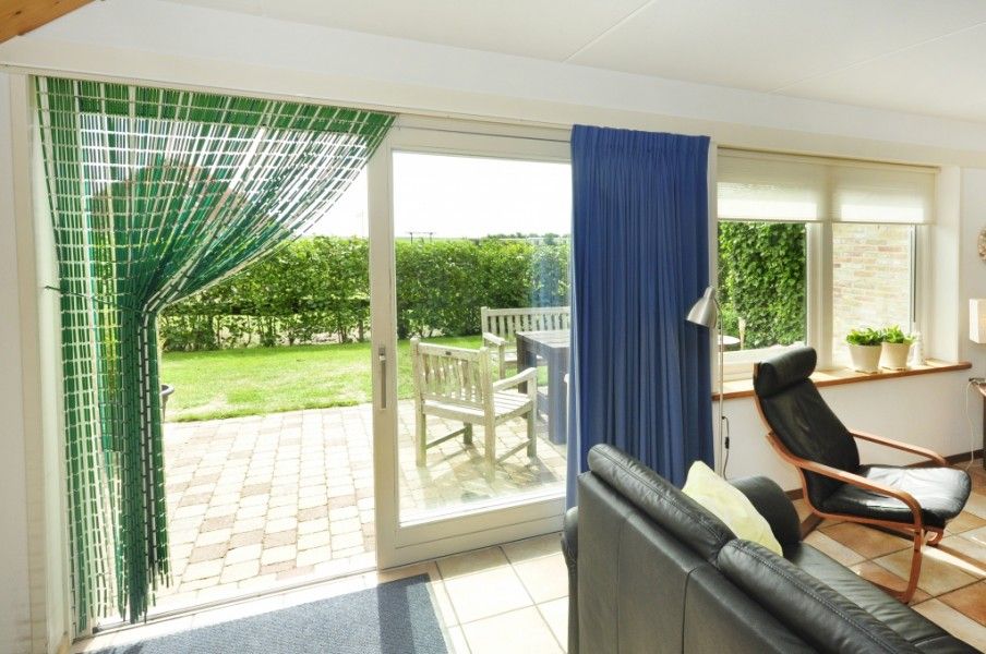 Zonnige veranda van Appartementenboerderij de Hek Oost, Hoorn, Terschelling met uitzicht op tuin.