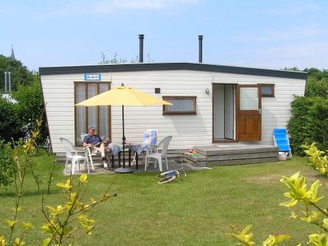Chalet De Stern in Hoorn, Terschelling, met zonnig terras en groene omgeving, ideaal voor ontspanning op de Waddeneilanden.
