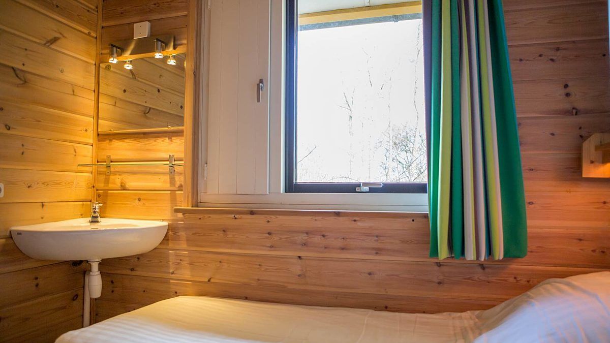 Knusse slaapkamer met houten interieur in Villabungalow, vakantiehuis in Oosterend, Terschelling, ideaal voor een ontspannen verblijf op de Waddeneilanden.
