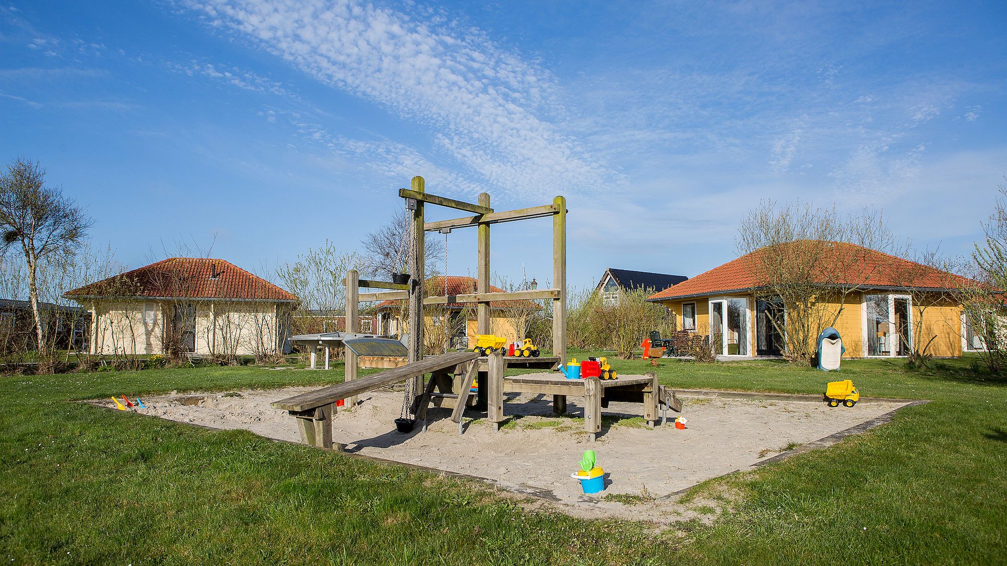 Speeltuin met zandbak bij Villabungalow, vakantiehuis in Oosterend, Terschelling, perfect voor kinderen in de natuurlijke omgeving van de Waddeneilanden.