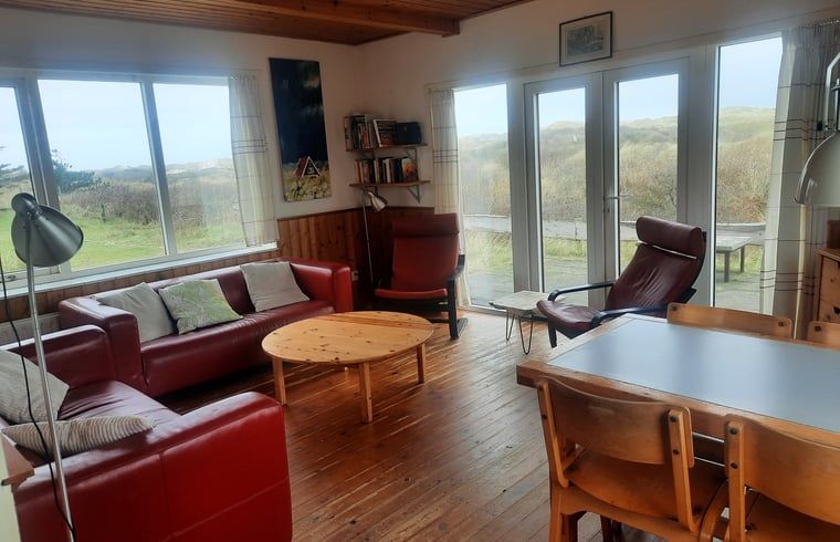 Gezellige woonkamer van Vakantiehuisje in West aan Zee op Terschelling met uitzicht op de duinen en comfortabele zitruimte.