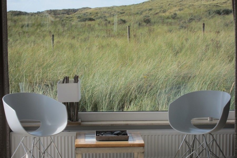 Rustige zithoek in Nij Jit vakantiehuis, Midsland aan Zee Terschelling, met uitzicht op groene duinen.