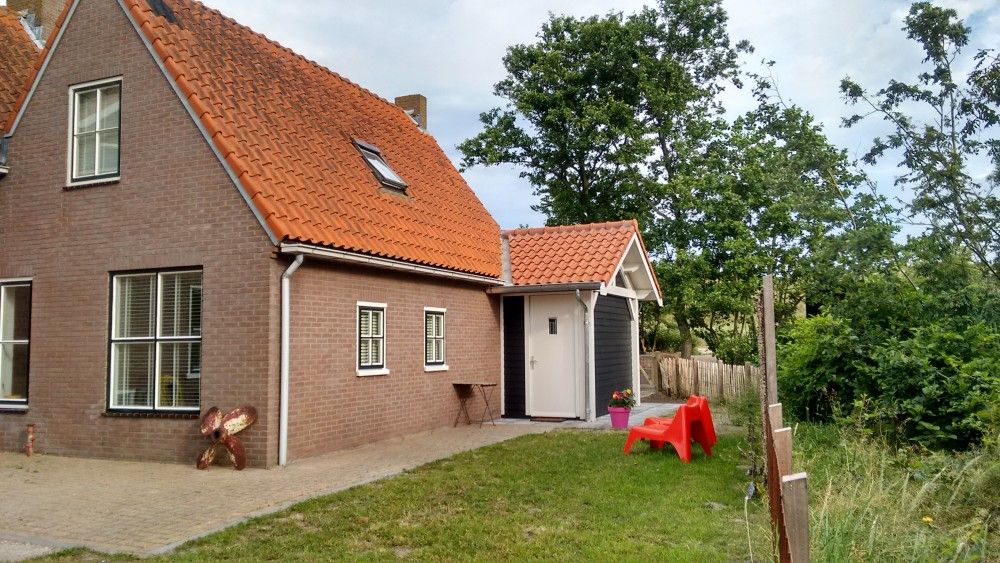 Rustieke buitenkant van vakantiehuis WadsEb.com in Klein Hoorn, Terschelling, omgeven door natuur.