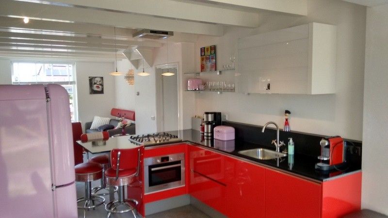Stijlvolle keuken in vakantiehuis WadsEb.com in Klein Hoorn, Terschelling, met rode accenten en moderne apparatuur.