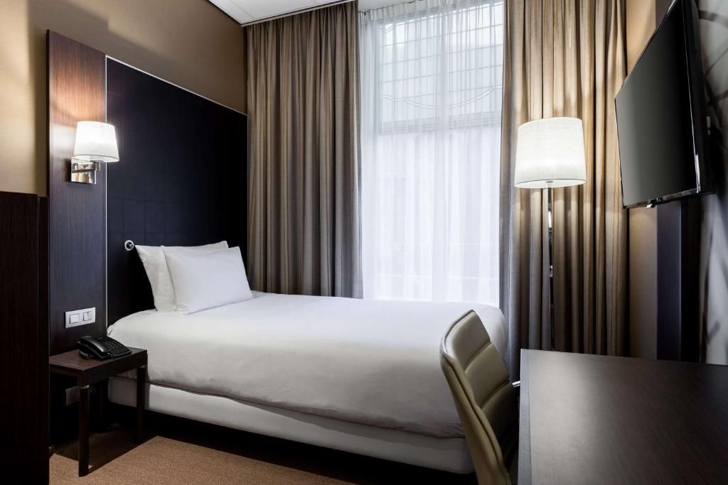 Badkamer met zowel douche als bad in NH Centre Utrecht Hotel, Utrecht, voor ultieme ontspanning.