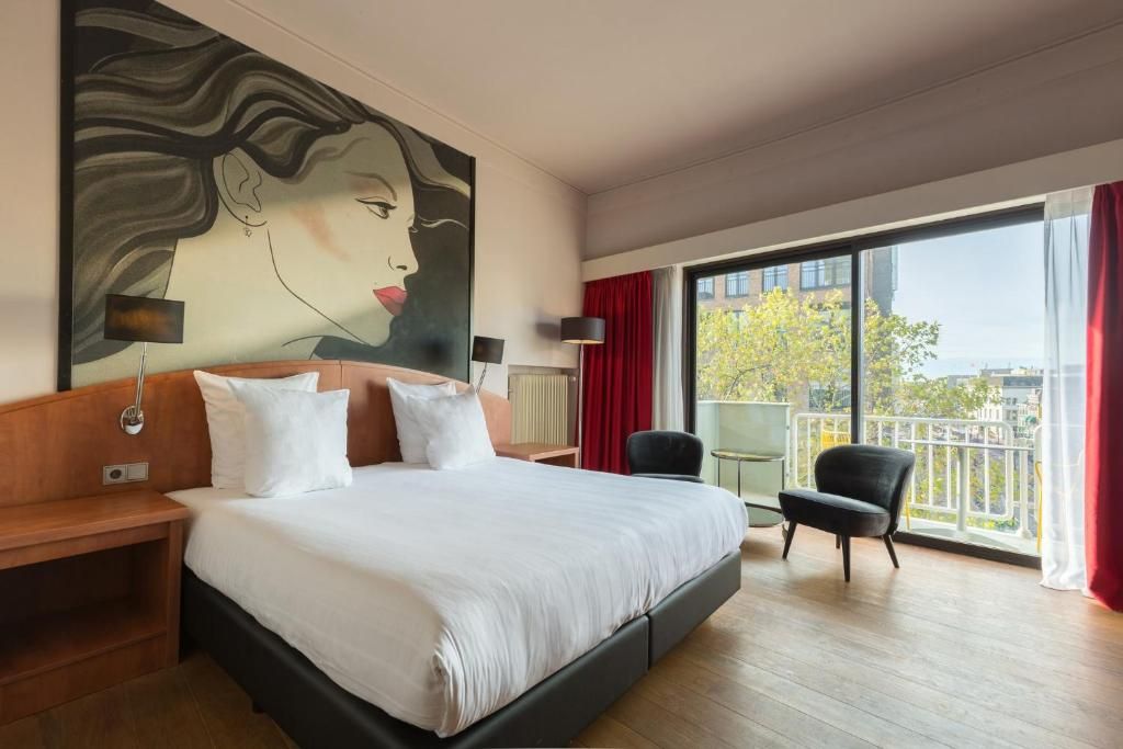 Luxe slaapkamer in Apollo Hotel Utrecht City Centre met balkon en uitzicht op Utrecht, ideaal voor een ontspannen verblijf.