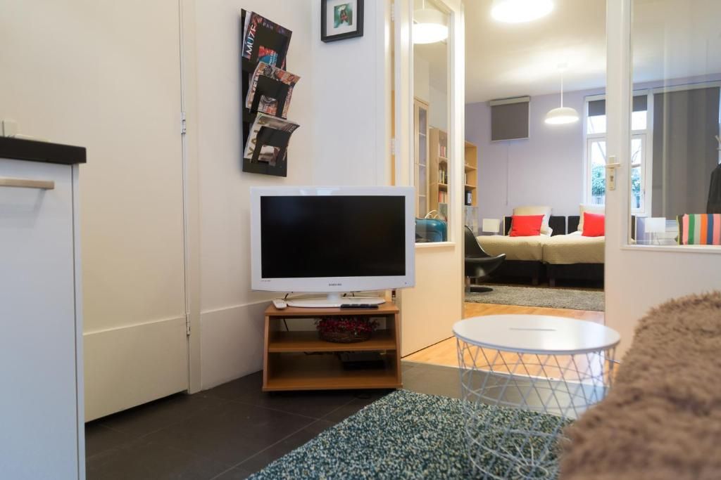 Knusse zithoek met tv in B&B Chez Cho, appartement in Utrecht, Utrecht eo, voor ontspanning na een dag verkennen.