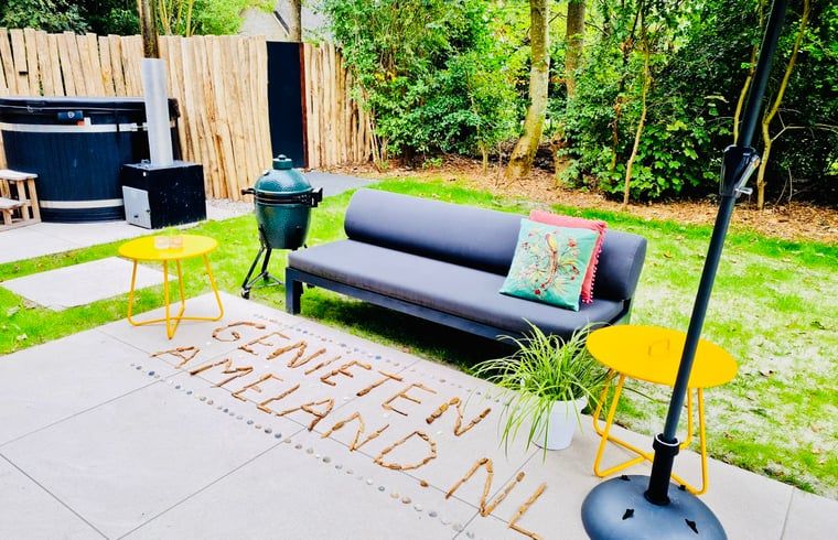 Aussenlounge im Ferienhaus in Ballum, Ameland, mit bequemen Sitzgelegenheiten und gruener Umgebung, ideal zum Entspannen.