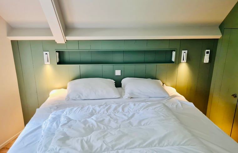 Attraktives Schlafzimmer im Ferienhaus in Ballum, Ameland mit komfortablem Bett und sanfter Beleuchtung fuer eine gute Nachtruhe.