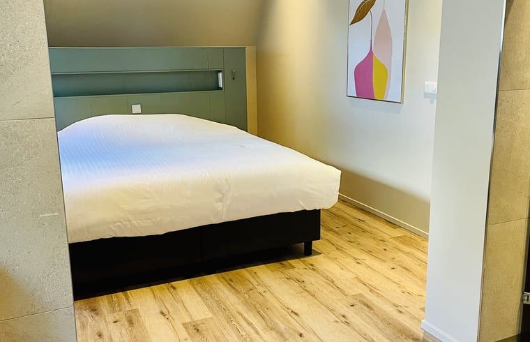 Schlafzimmer mit Holzboden im Ferienhaus in Ballum, Ameland, bietet Komfort und Stil auf den Watteninseln.