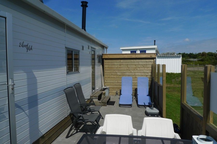 Spacious terrace at Eilandgeluk chalet in Ballum, Ameland, with deck chairs and views of the Wadden Islands nature.
