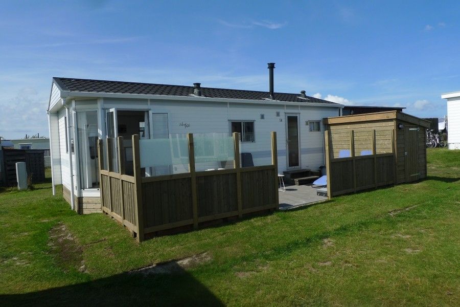 Exterior of Eilandgeluk chalet in Ballum, Ameland, with green surroundings and sunny terrace on the Wadden Islands.