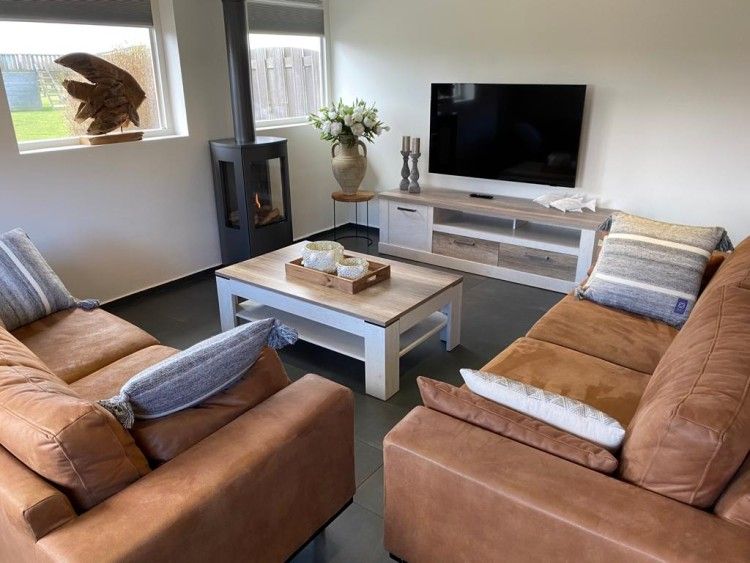 Modernes Wohnzimmer der Tree Lodge, Ballum, Ameland mit grossen Sofas und Flachbildfernseher.