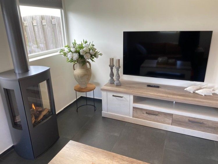 Stilvolle Ecke mit Kamin und TV in Tree Lodge, Ballum, Ameland zum Entspannen.