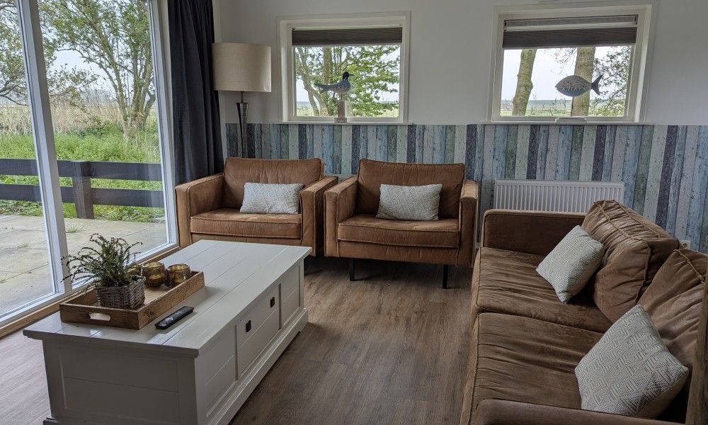 Gemuetliche Sitzecke in der Lodge 't Pandje, Ballum, Ameland mit Blick auf die Natur durch grosse Fenster.