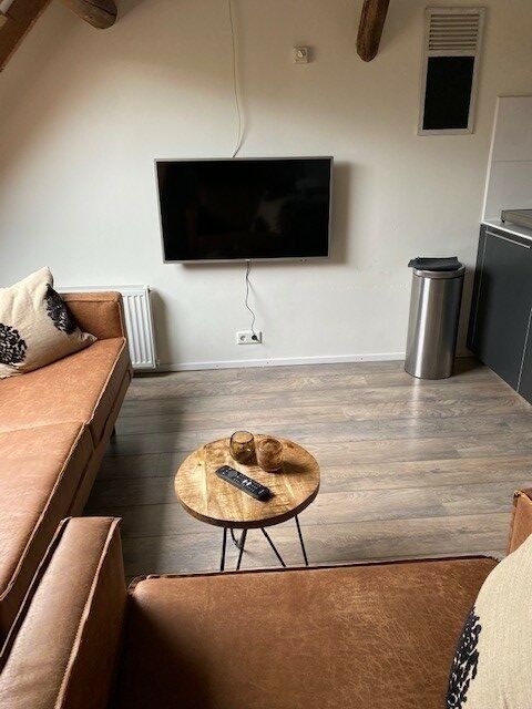 Gemuetlicher Innenbereich des Petit appartement, Ballum, Ameland mit Flachbildfernseher und Couchtisch aus Holz.