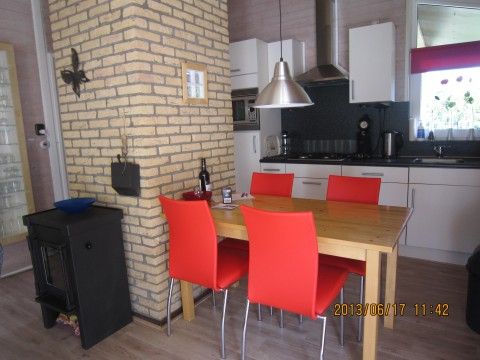 Moderne eetruimte in De Klipper vakantiehuis, Ballum, Ameland met rode stoelen.