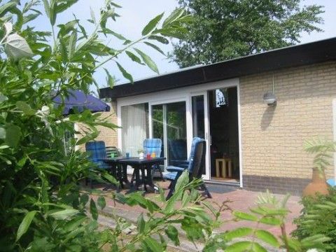 Zonnig terras van De Klipper vakantiehuis, Ameland met comfortabele stoelen en uitzicht op tuin.