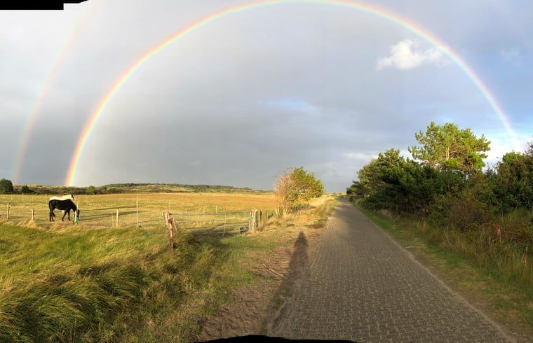 Adembenemende regenboog boven de velden bij Vakantiehuisje in Buren Ameland, een uniek natuurverschijnsel.