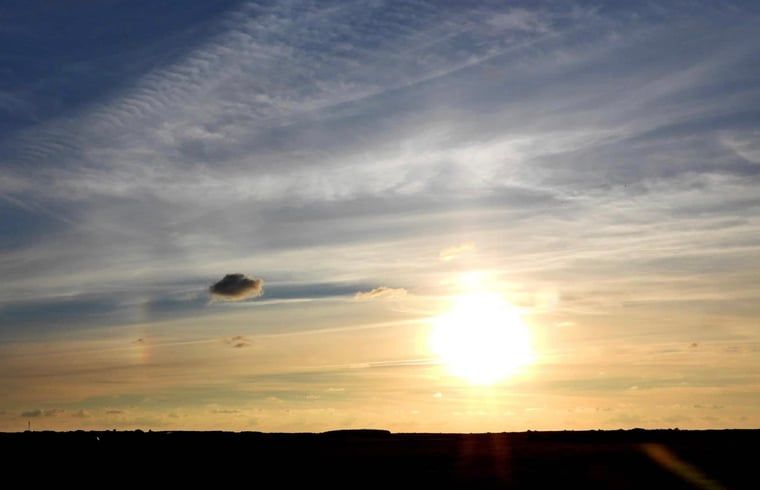 Heldere zonsondergang boven de velden bij Vakantiehuisje in Buren Ameland, een betoverend uitzicht.