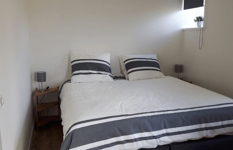 Comfortabele slaapkamer in Vakantiehuisje in Hollum op Ameland met een uitnodigend tweepersoonsbed en rustige sfeer.