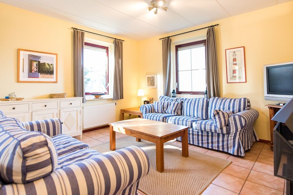 Gezellige woonkamer in Engelsmanduinvilla 8, een bungalow in Hollum, Ameland, met comfortabele banken en veel natuurlijk licht.