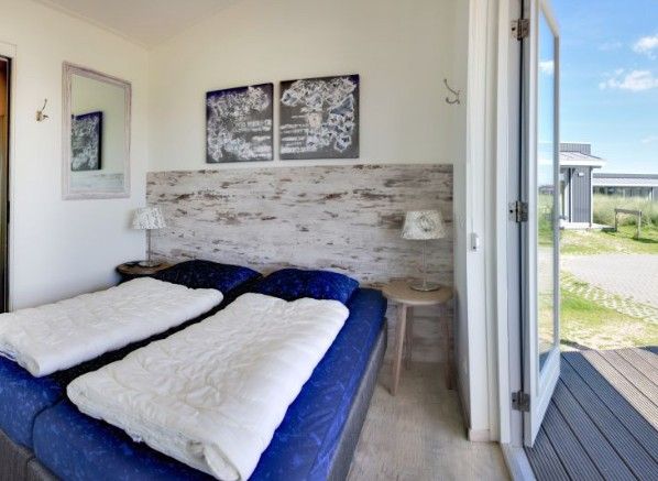 Schlafzimmer in Boomhiemke Haeuser, Hollum, Ameland mit Doppelbett und Blick auf die Terrasse.
