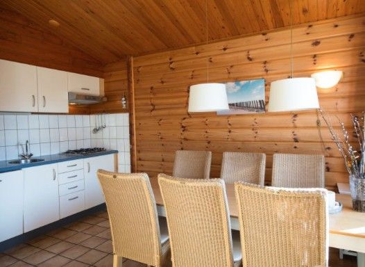 Esszimmer und Kueche des FINSE BUNGALOW 4 in Hollum, Ameland, mit hoelzernem Interieur und modernen Annehmlichkeiten.
