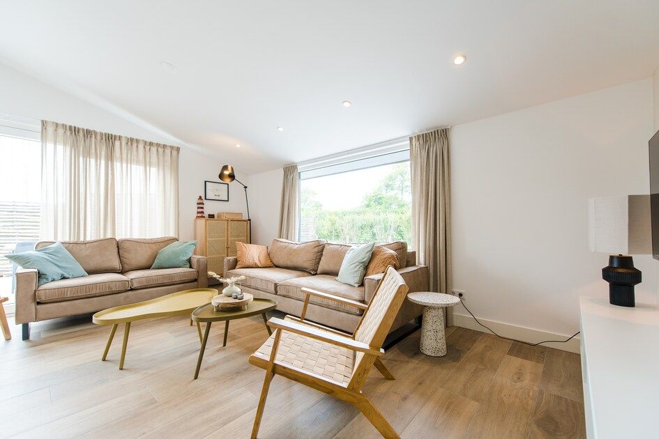 Gezellige woonkamer van Finse Bungalow Luxe 8 in Hollum, Ameland, met moderne inrichting en uitzicht op de natuurlijke omgeving.