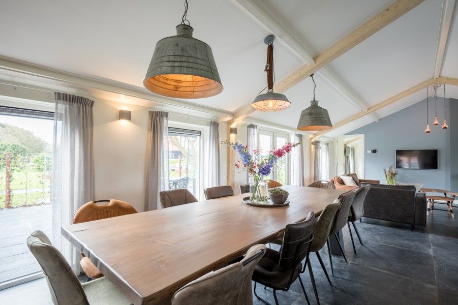 Gemuetliches Esszimmer im Bungalow Wagenschuur, Hollum, Ameland mit langem Tisch und Blick auf die Natur.