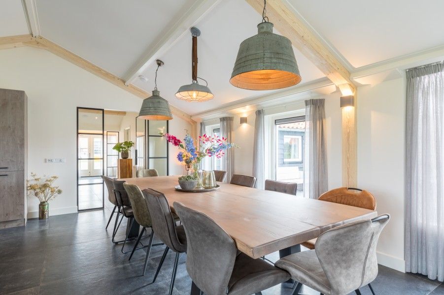 Heller Essbereich im Ferienhaus Wagenschuur, Hollum, Ameland mit grossen Fenstern und moderner Beleuchtung.