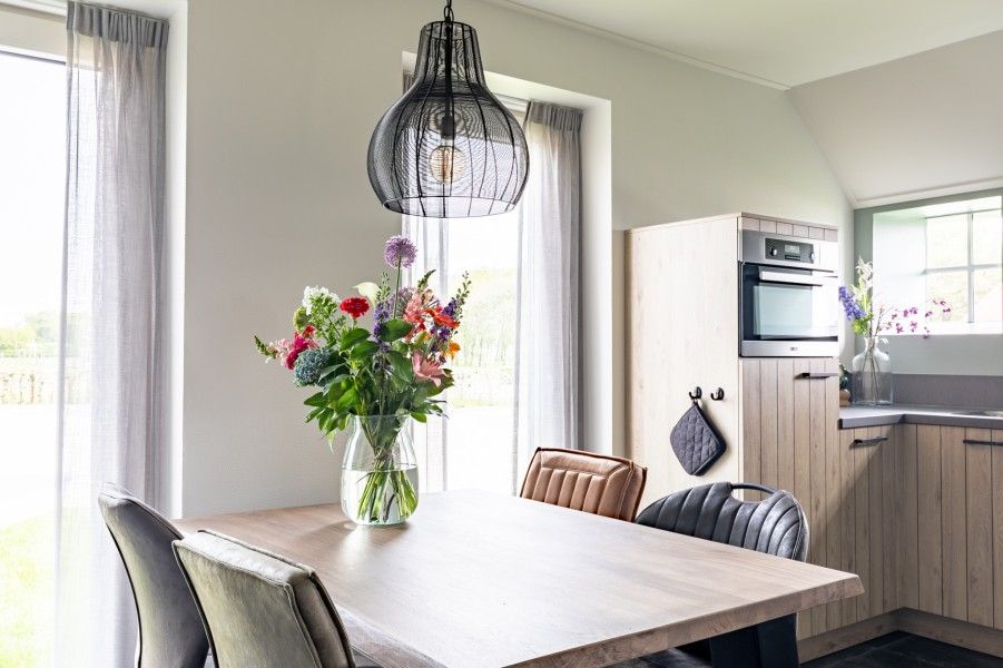 Gezellige eetruimte in De Deel, appartement in Hollum, Ameland met moderne inrichting en bloemen op tafel.