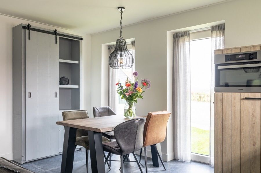 Stijlvolle eetkamer van De Deel, vakantieappartement in Hollum, Ameland, met houten tafel en designverlichting.