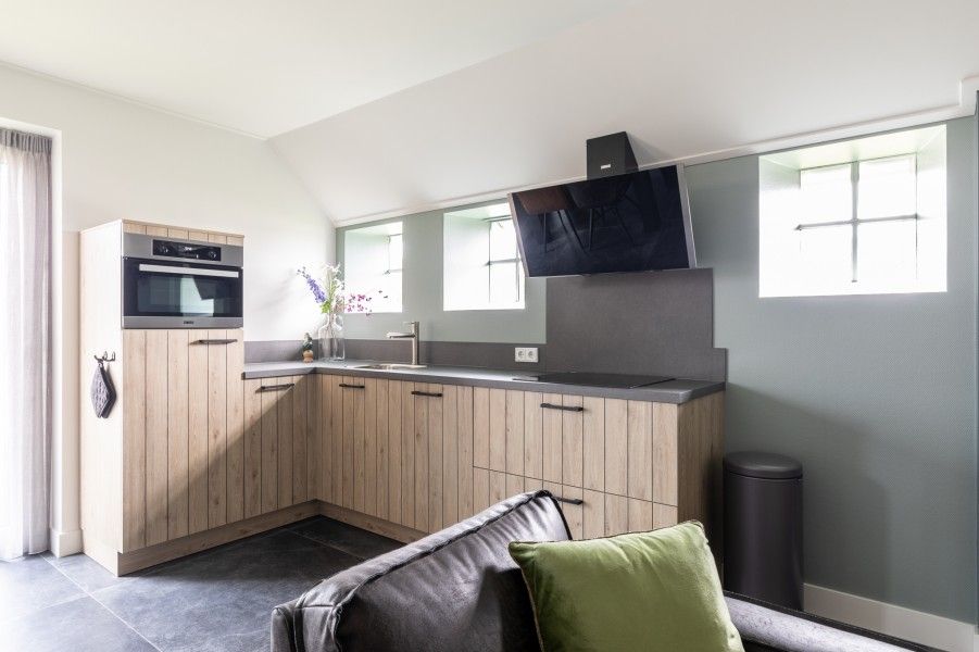 Moderne keuken in De Deel, appartement in Hollum, Ameland, met strakke houten kasten en veel lichtinval.