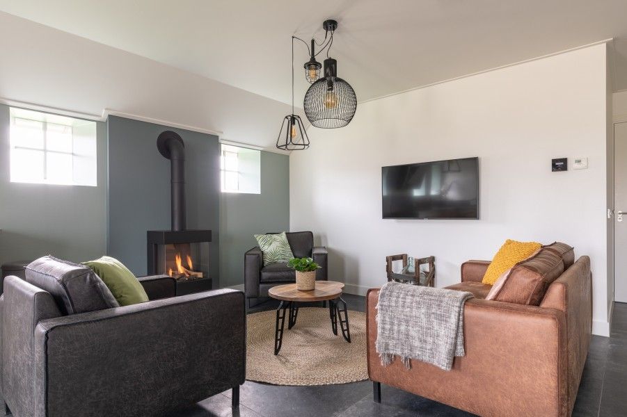 Comfortabele woonkamer van De Deel, appartement in Hollum, Ameland, met leren banken en een gezellige open haard.
