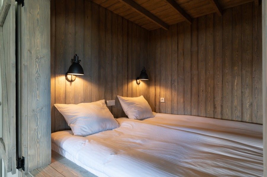 Gezellige slaaphoek in De Deel, appartement in Hollum, Ameland, met houten wanden en warme verlichting.