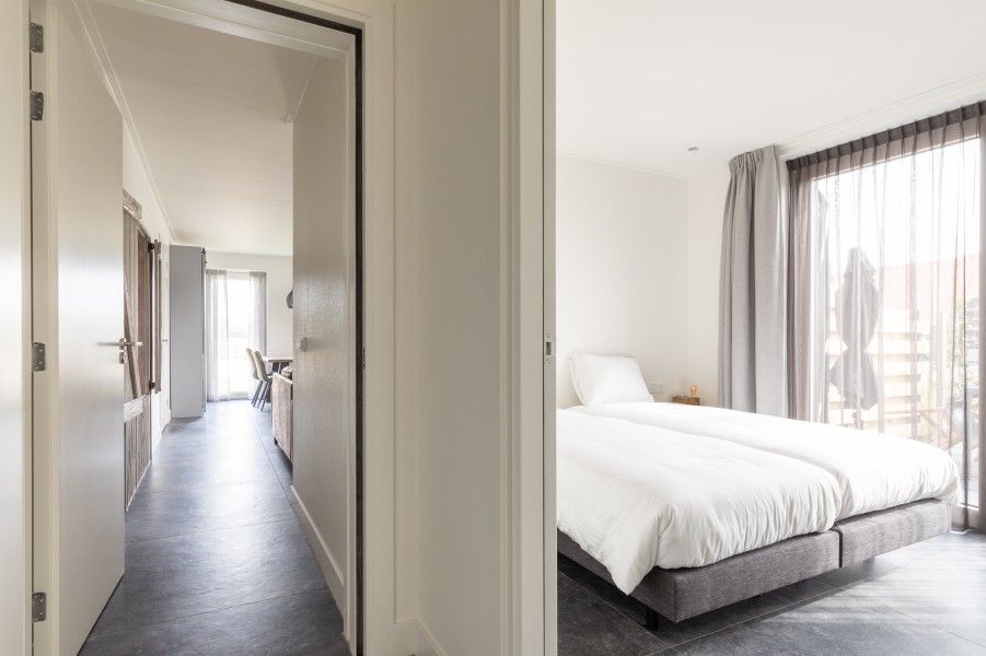 Lichte slaapkamer in De Deel, appartement in Hollum, Ameland, met groot bed en uitzicht op het terras.