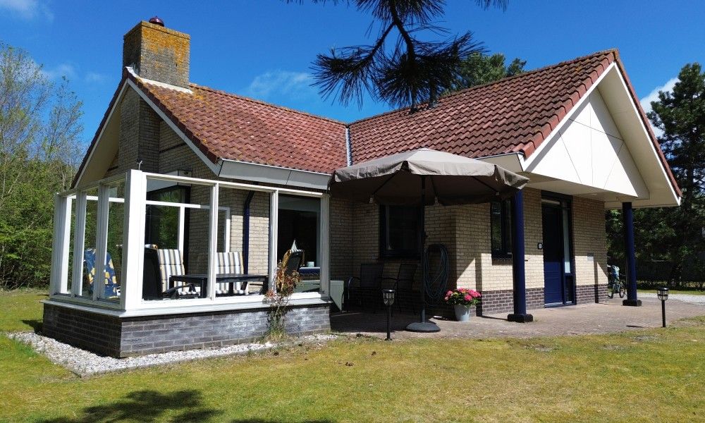 Luftaufnahme von "De Vrijheid", einem Ferienhaus in Hollum auf Ameland, umgeben von gruener Natur und nahegelegenen Duenen auf den Watteninseln.