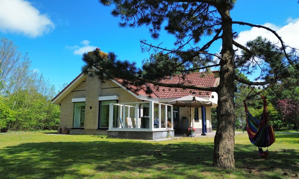 Gemuetliches Wohnzimmer des Ferienhauses "De Vrijheid" in Hollum auf Ameland, modern eingerichtet und mit Blick auf die gruene Umgebung.