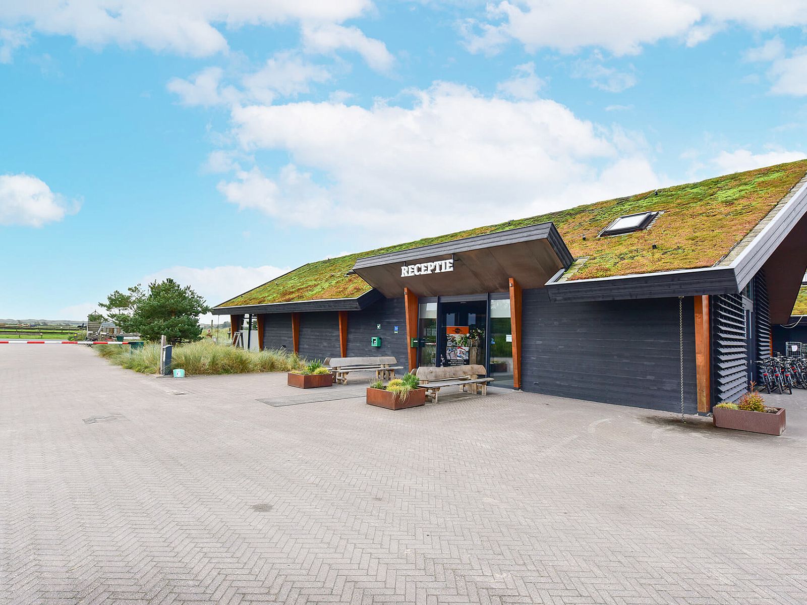 Receptie van vakantiepark in Hollum, Ameland, met groen dak en moderne architectuur.