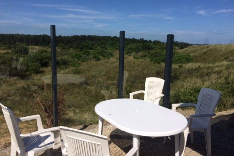 Terrasse des Parnassia-Bungalows in Nes, Ameland mit Blick auf die gruene Umgebung.