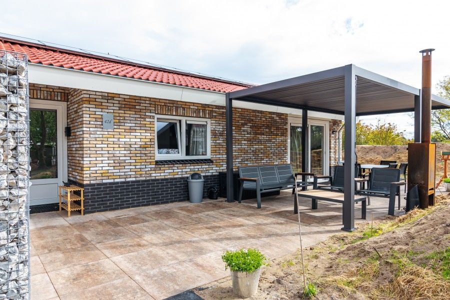 Veranda of vacation home Nesserduinen 42D in Nes, Ameland with modern seating area and canopy.